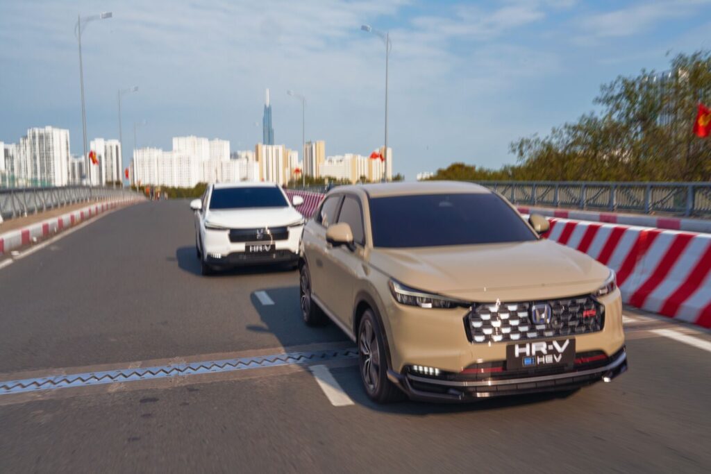 Honda HR-V e:HEV màu be vận hành trên cầu đô thị
